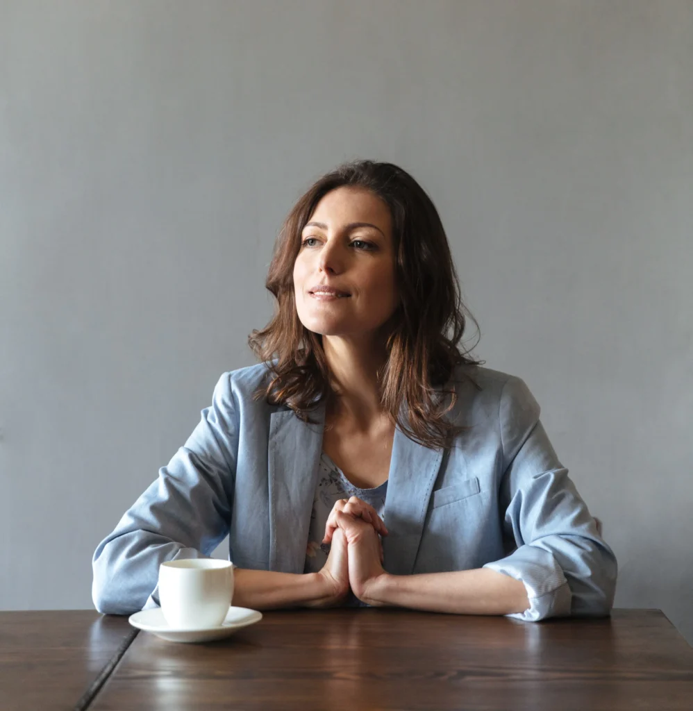 Concentrated woman sitting indoors near cup coffee